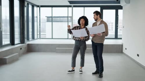Business Professionals Discussing Blueprints in a Modern Office Space