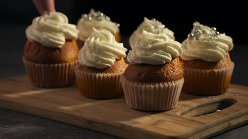 Close-up of frosting peaks on cupcakes with sprinkles, slow motion tracking left