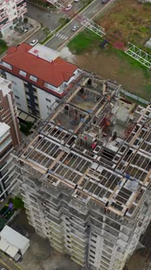 Vertical Video of Builders Working on Tall Structure With Crane