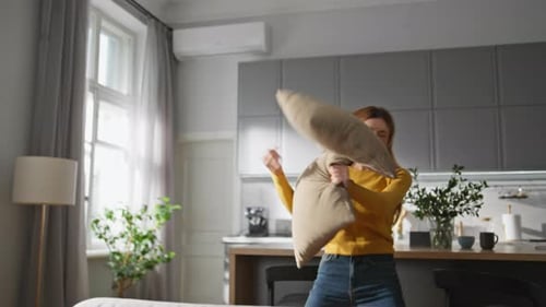 Woman Laughing and Throwing Pillows in Modern Apartment