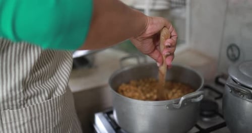 Hands Stirring Stew in a Silver Pot