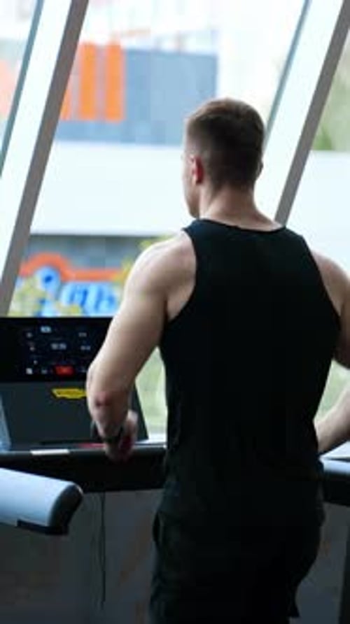 Man training legs in sport club. Young athletic man running on treadmill in sport gym