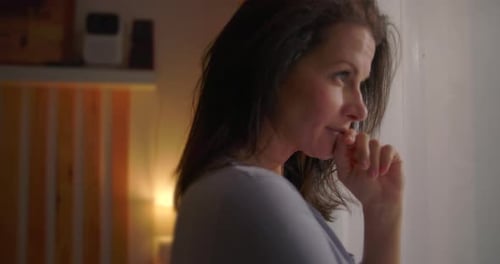 Pensive Woman Looks Out of Window Indoors