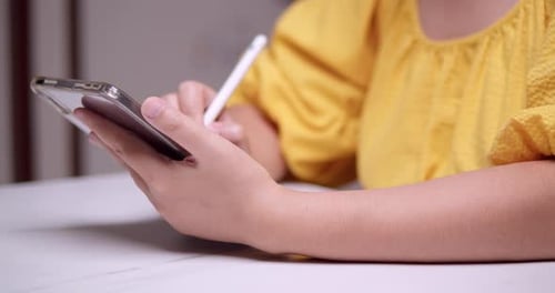 Detail weiblicher Hände, die mit Stift auf einem digitalen Tablet schreiben