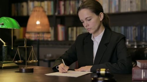 Woman Lawyer Writing at Desk in Law Office