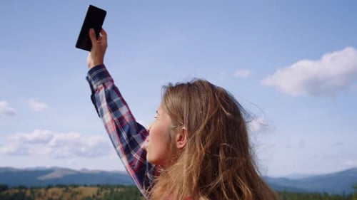 Sad Woman Holding Smartphone in Hand on Top of Mountain. Stressed Girl
