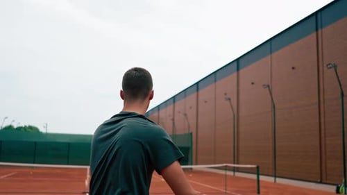young professional player coach on outdoor tennis court practices strokes with racket and ball