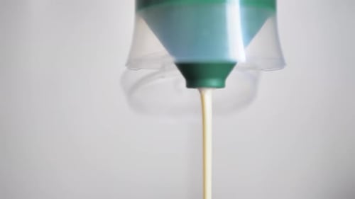White Liquid Being Dispensed from a Blue Container