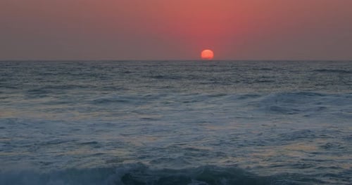 Slow motion Dramatic pink sunrise reflected over breaking waves at the beach, Durban, Kwazulu-Natal.