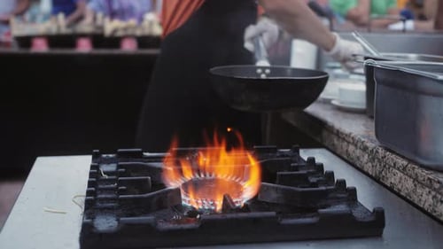 Chef Cooking with Fire in a Frying Pan at a Street Food Festival