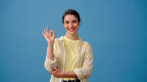 Happy Woman Making OK Sign on Blue Background