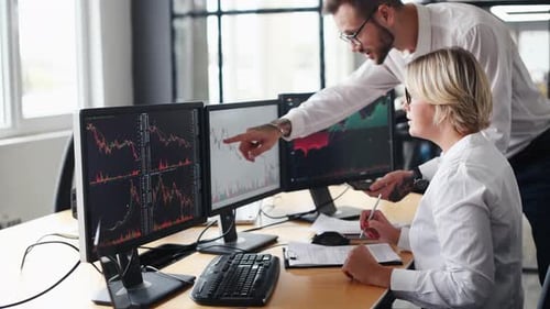 Man showing information on smartphone and display. Male and female stockbrokers in formal clothes