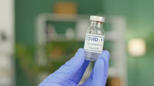 Gloved Hand Holds COVID-19 Coronavirus Vaccine Vial