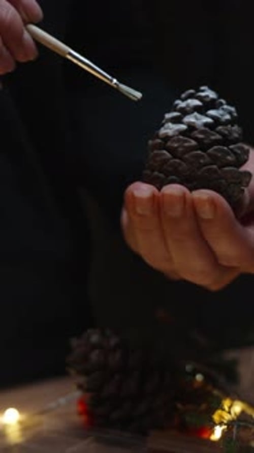 Vertical video. I apply white paint on a pine cone with a brush. Decorations for the house for the h