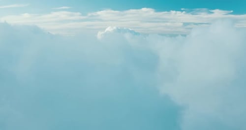 Aerial view ascending over misty blue clouds to reveal more clouds