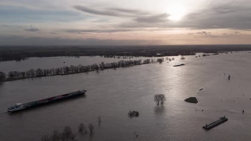 Silhouetted Ship on the Waal River Amidst Backlight and Submerged Floodplains