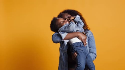 Smiling African American Mom Carrying Her Sweet Little Boy in Studio