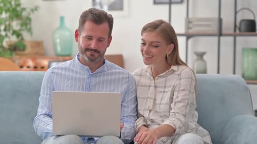 Couple Relaxing at Home Using Laptop Computer Together
