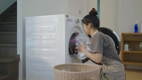 Woman Loading Clothes into Washing Machine at Home