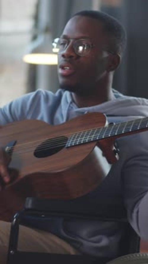Young Adult Plays Guitar in Wheelchair