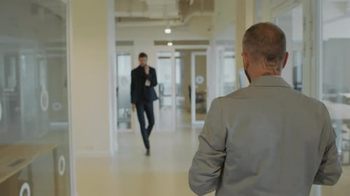 Two Businessmen Walking through Office Corridor and Shaking Hands