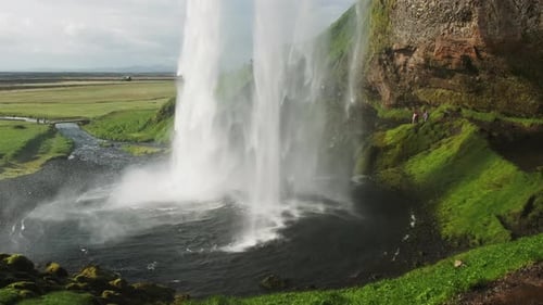 Tourists exploring beautiful Seljalandsfoss Waterfall In Iceland