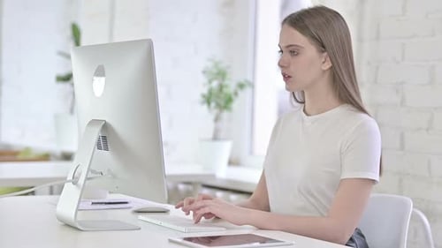 Young Woman Typing at Computer in Office