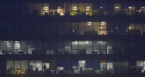 Ventanas de oficina a altas horas de la noche que brillan en un rascacielos oscuro de una ciudad