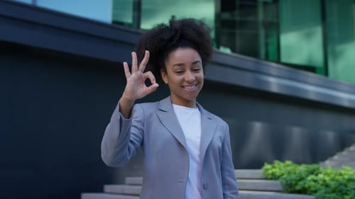 Smiling Young Adult Makes 'Okay' Sign in Urban Setting
