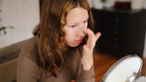 Teenager-Mädchen schminkt sich und schaut in den Spiegel Schöne Teenagerin, die ihr Gesicht pflegt, 14 Jahre alte Frau