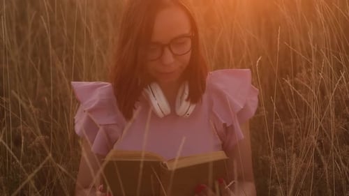Woman Reads Book in Golden Field at Sunrise
