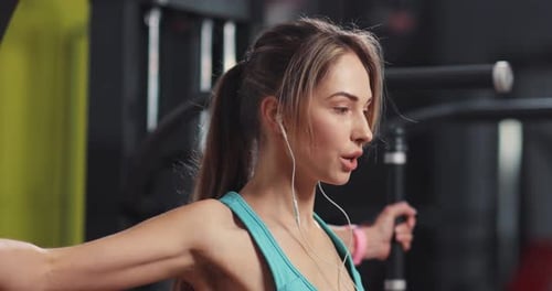 Young Woman Listening to Music in Headphones Engaged in a Gym Girl Person Sport Fitness Workout