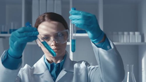 Científica atenta en un laboratorio avanzado con tubos de ensayo en las manos y equipo de investigación