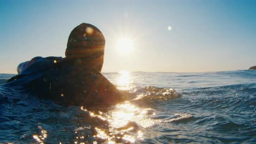 Male Surfer Paddles in the Ocean at Sunrise