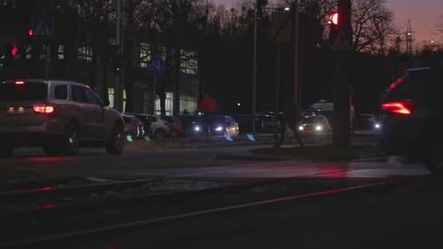 Un automóvil espera en el semáforo en rojo mientras los peatones atraviesan el paso peatonal de cebra. Una noche lenta en un
