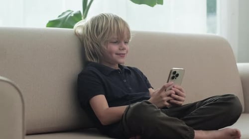 Boy Relaxing on Couch Using Mobile Phone