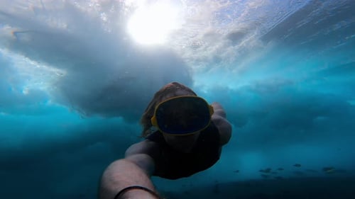 Brave Man Diving Under Big Wave In Rough Ocean Water During A Stormy Day Swim