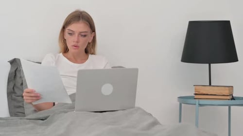 Woman Celebrates Good News in Bed With Laptop
