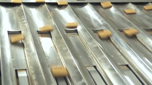 lots of square cookies slide down a metal plate