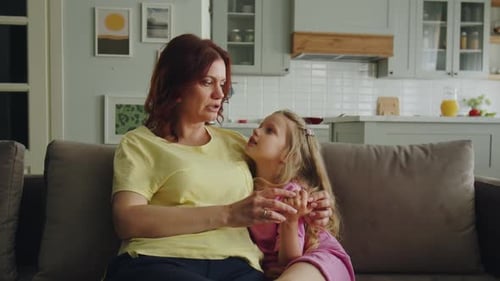 Mother and Daughter Talking Affectionately on Sofa at Home