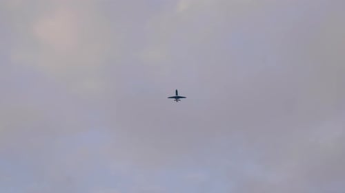 Bottom View Of An Airplane Flying In Clouded Sky. low angle, tracking shot