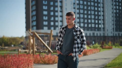 Young Man Strolls During Sunny Day Near Playground in Urban Residential Park