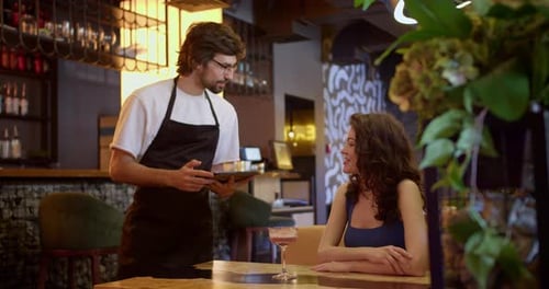 Woman Ordering at Restaurant from Smiling Waiter