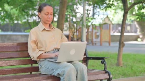 Young Woman Smiling with Laptop in Park