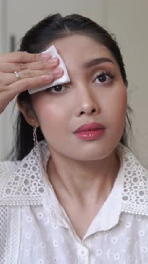 Happy young Asian woman applying make up remover and skincare to remove her make up.