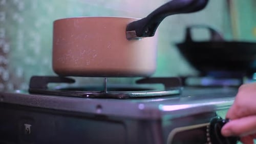Kitchen one small burner turning on stove, cooking home flame, hand turns natural gas with pan
