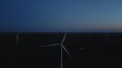 Aerial Wide Shot of a Close Up Wind Turbine Standing in a Wheat Field at Night Time