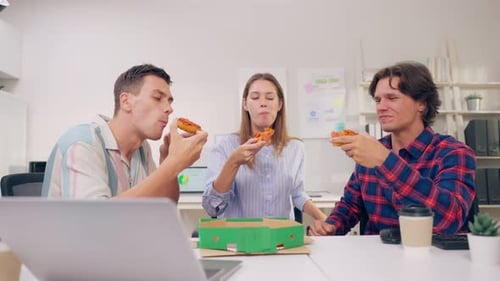 Group of businessman and woman eat pizza while working in the office.