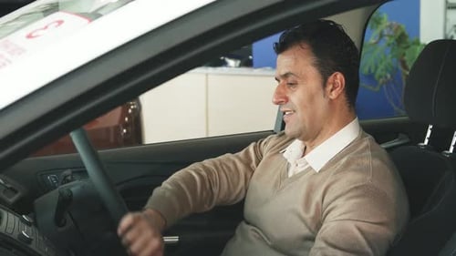 Man Sits in New Car and Smiles