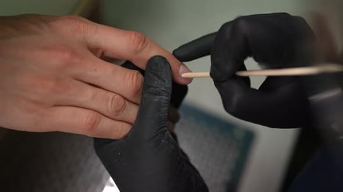 Closeup Top View of Skilled Beautician Wearing Black Gloves Removing Cuticles From Fingernails of